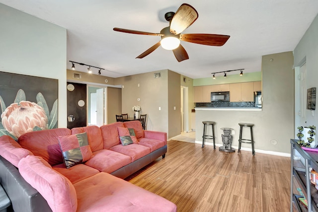 living room with light hardwood / wood-style floors, track lighting, and ceiling fan