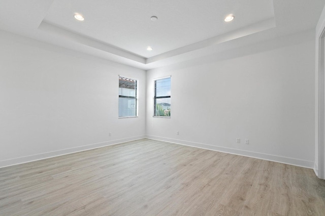 spare room with light wood-type flooring and a raised ceiling