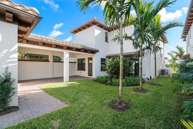 back of property with a patio area, central AC, and a lawn