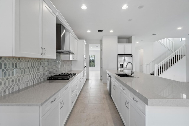 kitchen with white cabinetry, wall chimney exhaust hood, sink, and appliances with stainless steel finishes