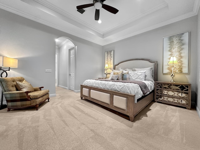 carpeted bedroom with ornamental molding, a tray ceiling, and ceiling fan