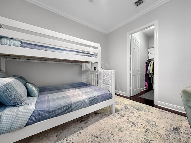 bedroom featuring a closet, ornamental molding, dark wood-type flooring, and a walk in closet