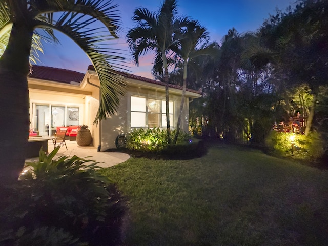 property exterior at dusk featuring a patio and a yard