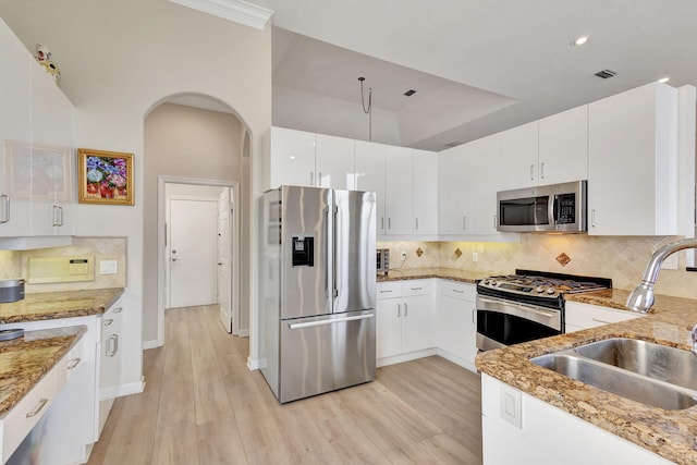 kitchen with stainless steel appliances, sink, light stone countertops, light wood-type flooring, and white cabinets