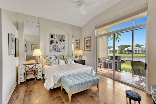 bedroom with access to exterior, ceiling fan, vaulted ceiling, a water view, and hardwood / wood-style flooring