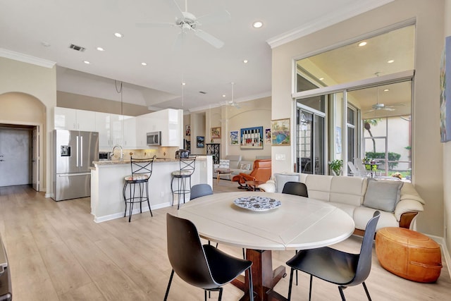 dining space featuring sink, crown molding, light hardwood / wood-style flooring, and ceiling fan