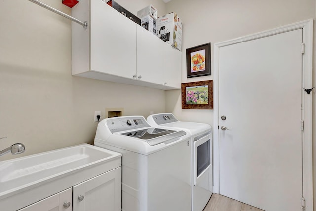 washroom featuring sink, light wood-type flooring, separate washer and dryer, and cabinets