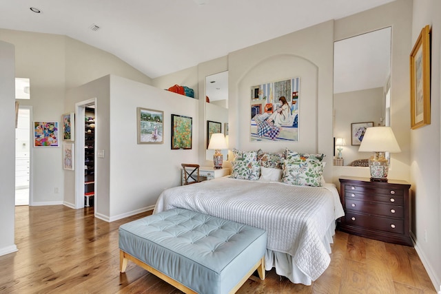 bedroom with light hardwood / wood-style flooring, a spacious closet, and lofted ceiling