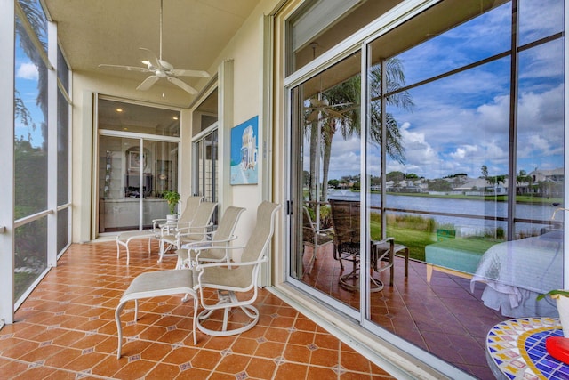 sunroom featuring a water view and ceiling fan