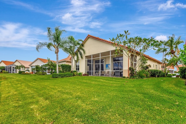 rear view of property with a sunroom and a lawn