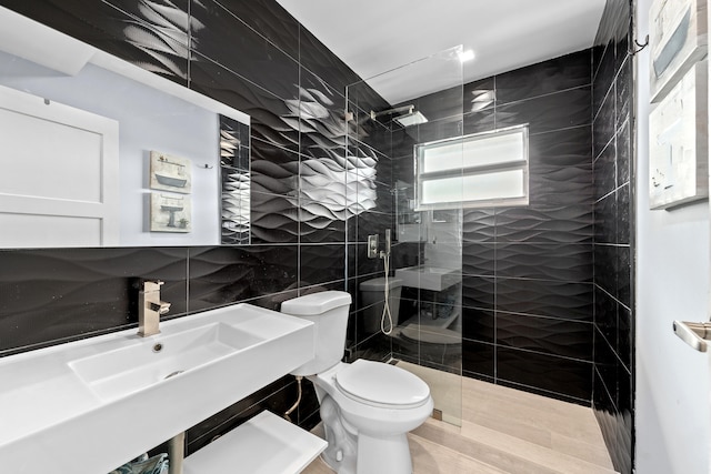 bathroom with hardwood / wood-style floors, a tile shower, tile walls, toilet, and sink