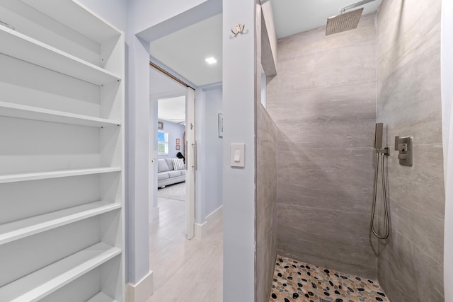 bathroom with hardwood / wood-style floors and a tile shower