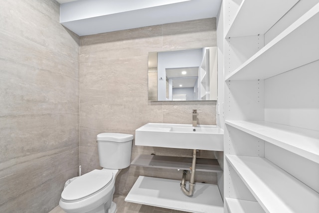 bathroom featuring toilet, sink, and tile walls