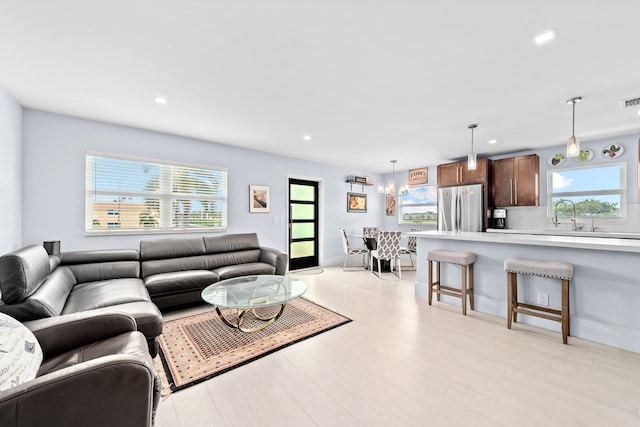 living room with an inviting chandelier, light hardwood / wood-style flooring, and a healthy amount of sunlight