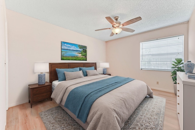 bedroom with a textured ceiling, light hardwood / wood-style floors, and ceiling fan