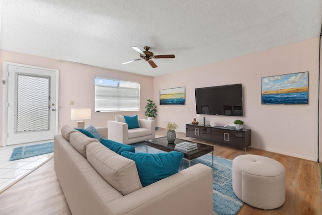 living room featuring ceiling fan, a textured ceiling, and light hardwood / wood-style flooring