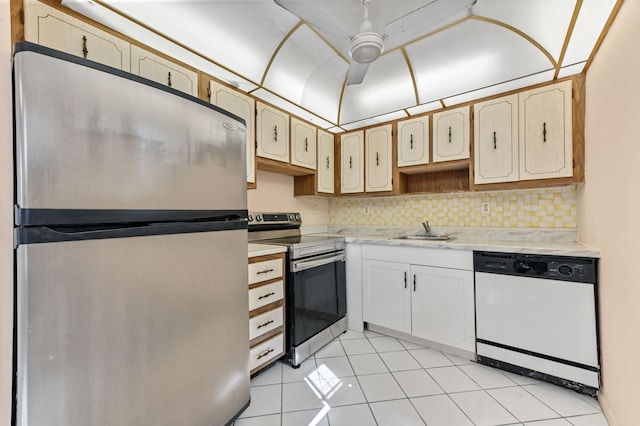 kitchen featuring decorative backsplash, stainless steel appliances, sink, light tile patterned floors, and white cabinets