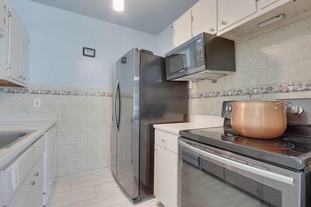 kitchen with white cabinets, black appliances, and tile walls