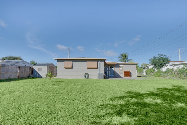 back of house featuring a yard and a shed