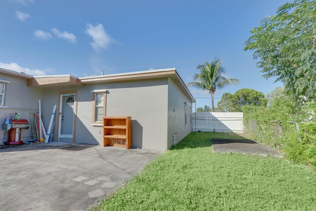 back of house with a lawn and a patio