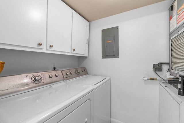 laundry room with electric panel, washing machine and clothes dryer, and cabinets