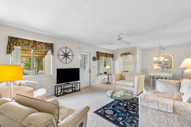 living room featuring carpet, a textured ceiling, and ceiling fan with notable chandelier