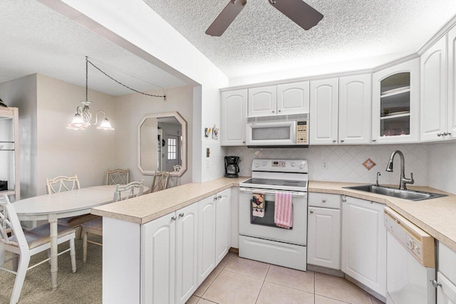 kitchen with white cabinets, kitchen peninsula, pendant lighting, and white appliances