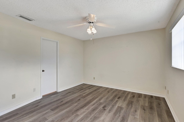 empty room featuring dark wood-type flooring, a textured ceiling, and ceiling fan