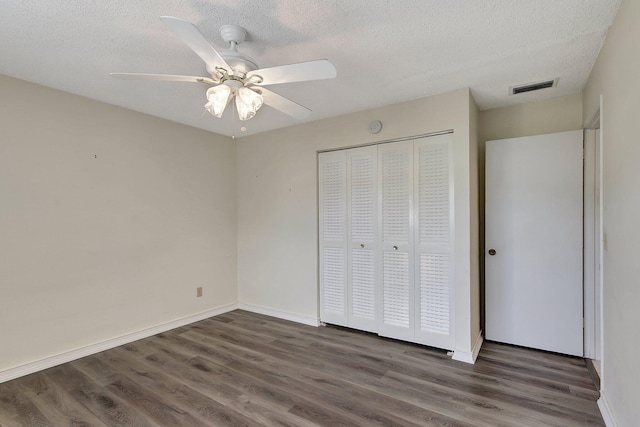 unfurnished bedroom with a closet, ceiling fan, a textured ceiling, and dark hardwood / wood-style floors