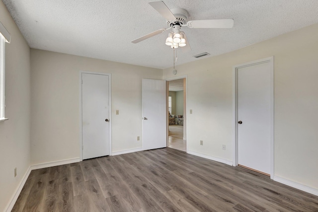 unfurnished bedroom with ceiling fan, a textured ceiling, and dark hardwood / wood-style floors