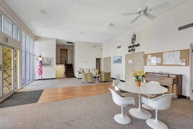 dining space with a towering ceiling, light hardwood / wood-style floors, and ceiling fan