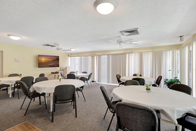 carpeted dining space with a textured ceiling and ceiling fan