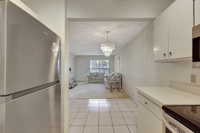 kitchen featuring white cabinetry, stainless steel appliances, light colored carpet, and hanging light fixtures