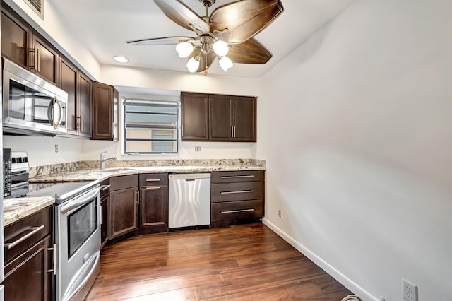 kitchen featuring ceiling fan, appliances with stainless steel finishes, light stone countertops, dark hardwood / wood-style floors, and sink