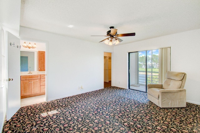 carpeted bedroom featuring access to exterior, a closet, a walk in closet, a textured ceiling, and ceiling fan