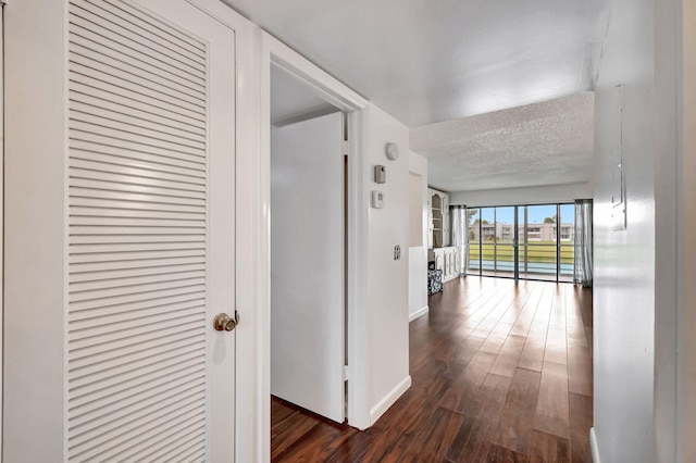 corridor with a textured ceiling and dark hardwood / wood-style flooring