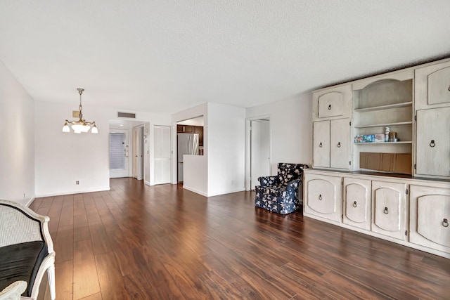 unfurnished living room featuring a textured ceiling, a chandelier, and dark hardwood / wood-style floors