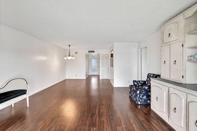 unfurnished living room featuring a textured ceiling, a notable chandelier, and dark hardwood / wood-style floors