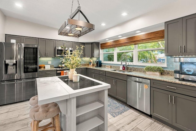 kitchen featuring light hardwood / wood-style flooring, gray cabinetry, stainless steel appliances, sink, and a center island