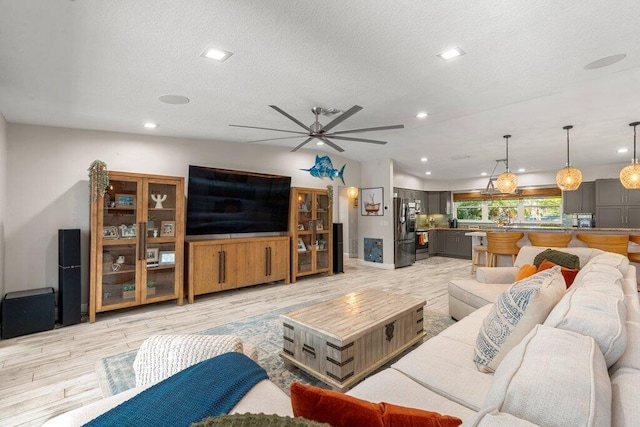 living room featuring a textured ceiling, light wood-type flooring, and ceiling fan