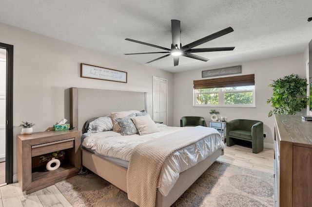 bedroom with light hardwood / wood-style flooring, a textured ceiling, a closet, and ceiling fan