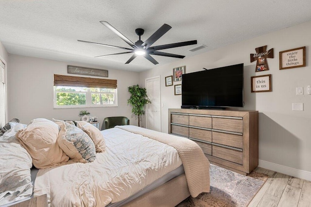 bedroom with light hardwood / wood-style flooring, a textured ceiling, and ceiling fan