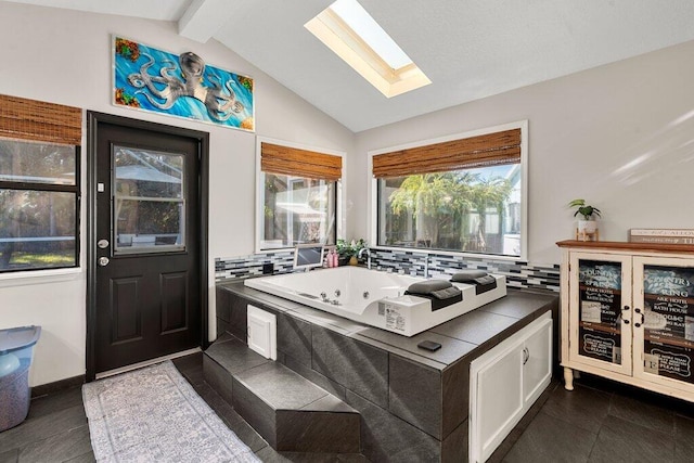 interior space with lofted ceiling with skylight, white cabinets, and dark tile patterned flooring