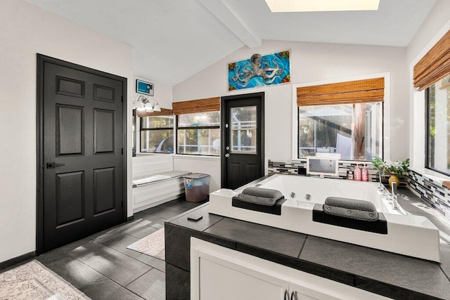 bathroom featuring vaulted ceiling with skylight, a bathtub, and tile patterned flooring