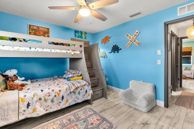 bedroom featuring a textured ceiling, wood-type flooring, and ceiling fan