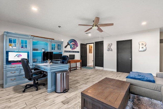 office area featuring built in desk, light wood-type flooring, and ceiling fan