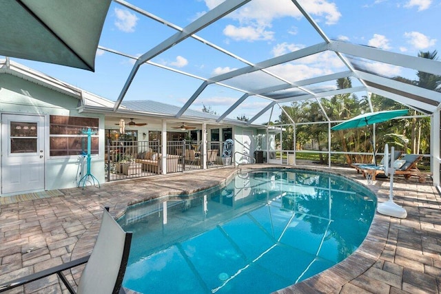 view of pool with a patio, glass enclosure, and ceiling fan