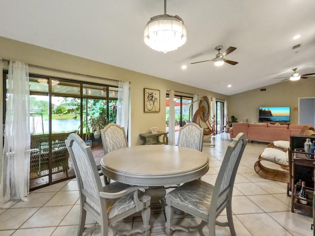 dining room with light tile patterned floors, ceiling fan with notable chandelier, and vaulted ceiling