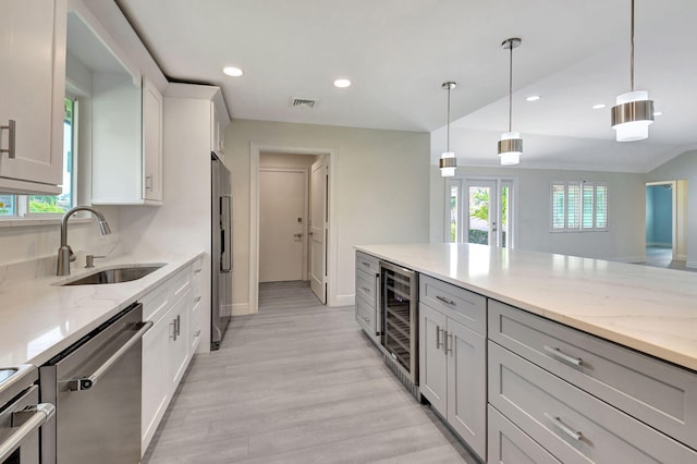 kitchen featuring light stone countertops, wine cooler, appliances with stainless steel finishes, and light hardwood / wood-style flooring