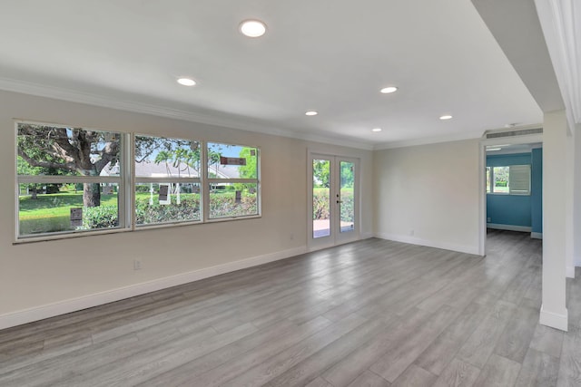 empty room featuring crown molding, plenty of natural light, and light wood-type flooring